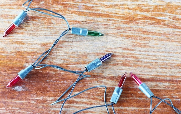Close-up shot of an EVA foam prop with embedded LED strip lights, wires neatly arranged and connected to a small battery pack with a power switch. The lights are emitting a soft blue glow, illuminating the surrounding foam edges.
