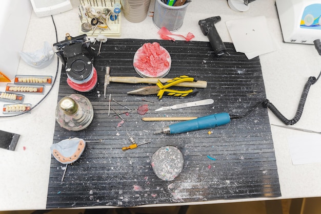 A workbench with various foam pieces cut to shape for Sevika's arm modifications. Tools such as a heat gun, cutting mat, and contact cement are visible.