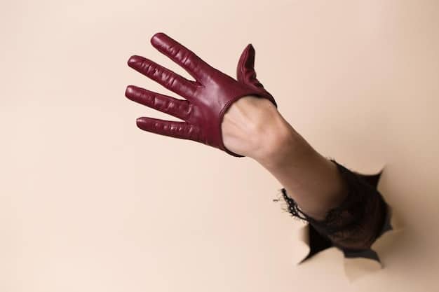 A close-up shot of a cosplayer's gloved hand, specifically showcasing fingerless gloves with distressed details. The lighting is focused on the texture and design of the gloves, highlighting their practicality and worn look.