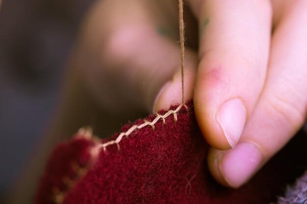 A detailed image showing a cosplayer's hands carefully adding decorative stitching to a dark vest. Close-up focuses on the needle, thread, and fabric texture.