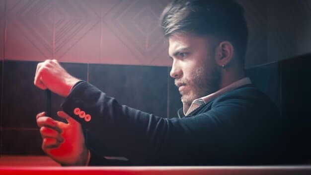 A photograph of a professional League of Legends player intensely focused on their screen during an LCS match. The player is wearing a team jersey and surrounded by high-end gaming equipment. The lighting is focused on the player's face, emphasizing their concentration.