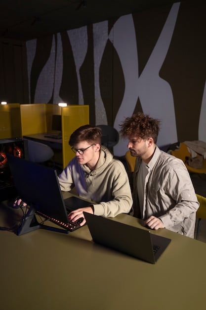 A shot of a data analyst working with a coach in an esports team's training facility. The analyst is pointing at a screen showing performance data, while the coach is listening attentively, notepad in hand. The scene highlights the collaborative environment and the integration of data analysis into the coaching process.