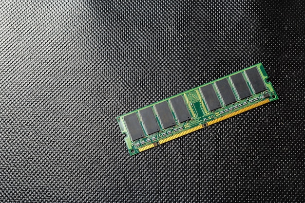 A detailed view of a DDR5 RAM stick, highlighting its distinct notched connector and heat spreader design, contrasting it with a blurred DDR4 stick in the background to show the generational difference.