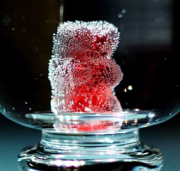 A close-up of a filled custom water cooling reservoir with no air bubbles visible, demonstrating a successful bleeding process, with clear, vibrant coolant.